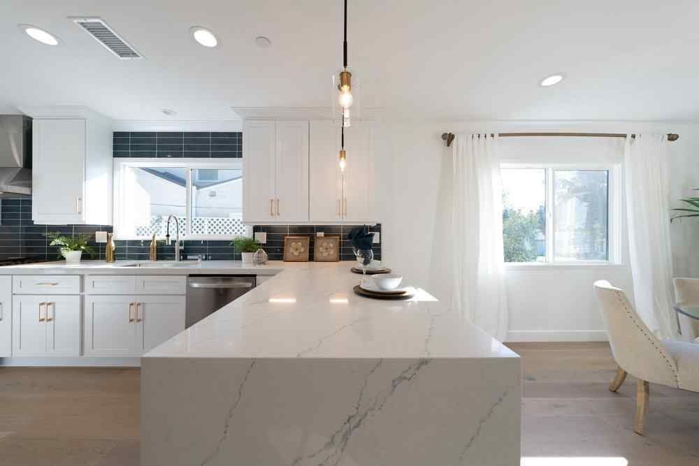 Bright modern kitchen with white cabinets, island, and window.