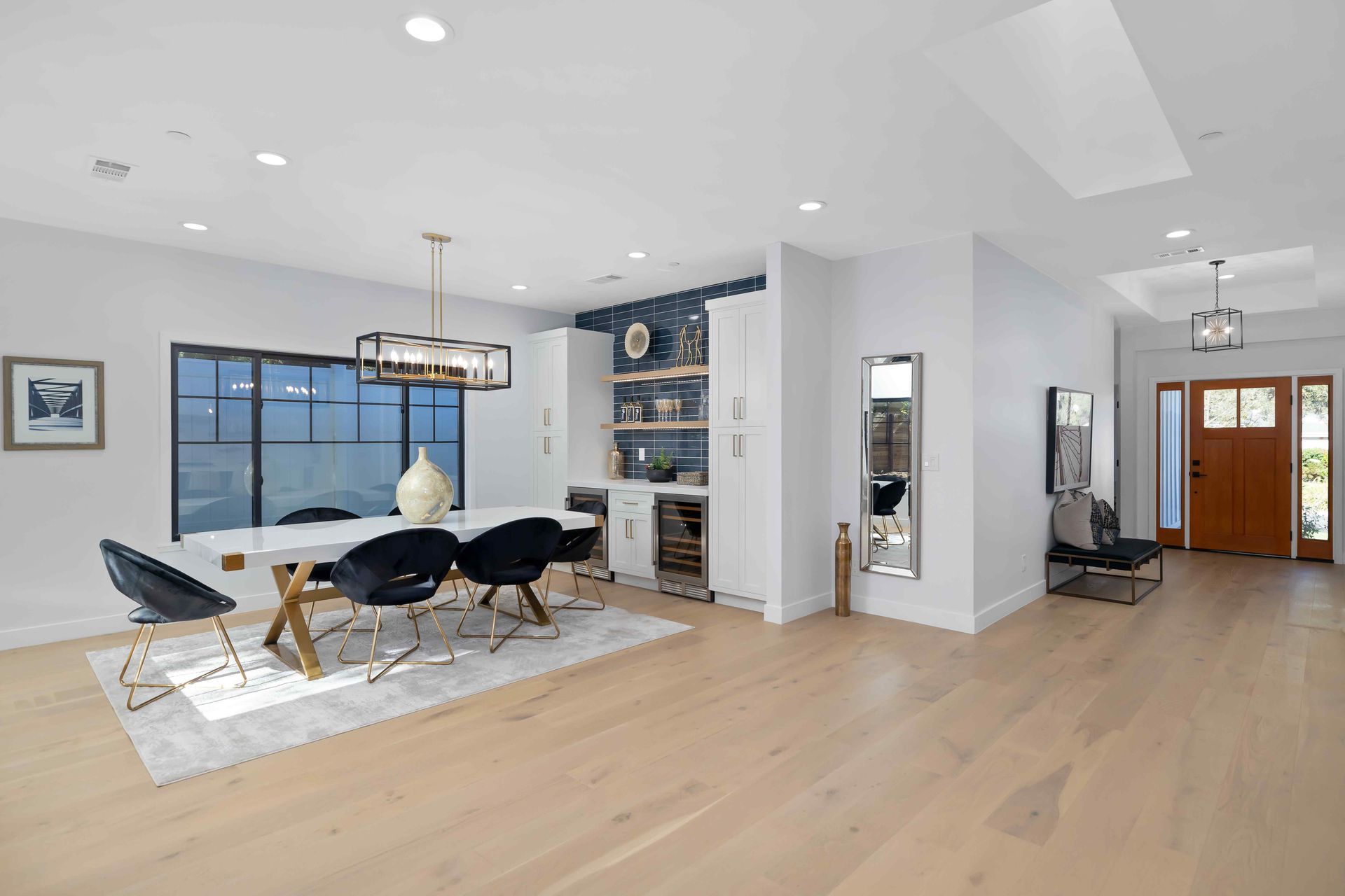 Modern dining room with white walls, light wood floors, and a table set for dining.