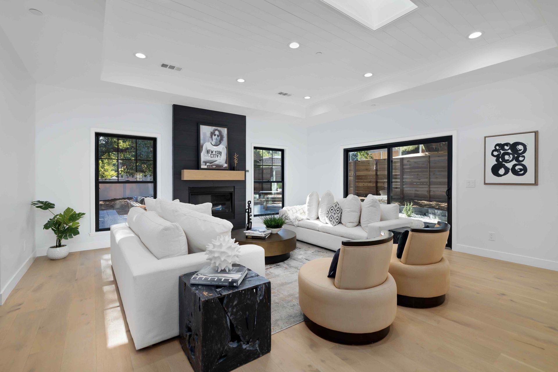 Spacious modern living room with white walls, a fireplace, and light wood floors.