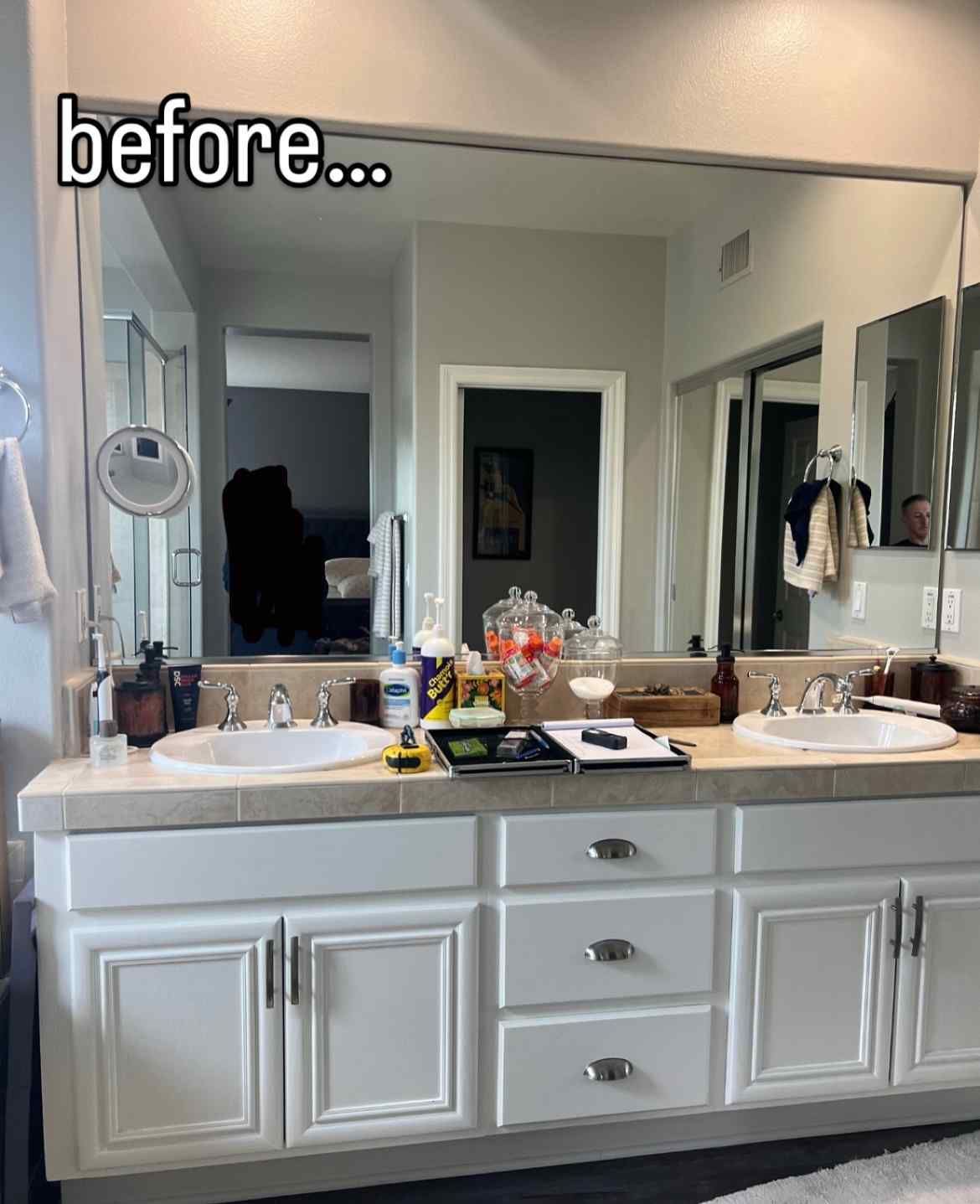 Bathroom with large mirror above a white vanity with two sinks. Gray walls.