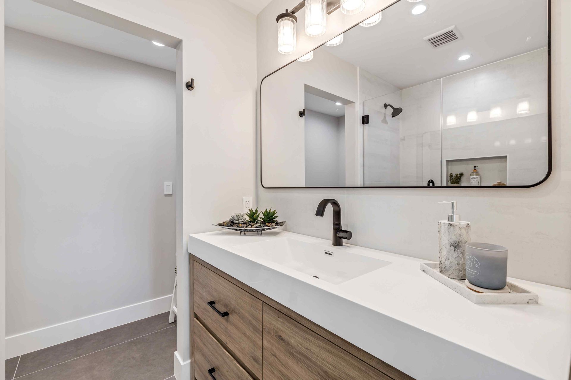 Modern bathroom with a light wood vanity, white countertop, and large mirror.