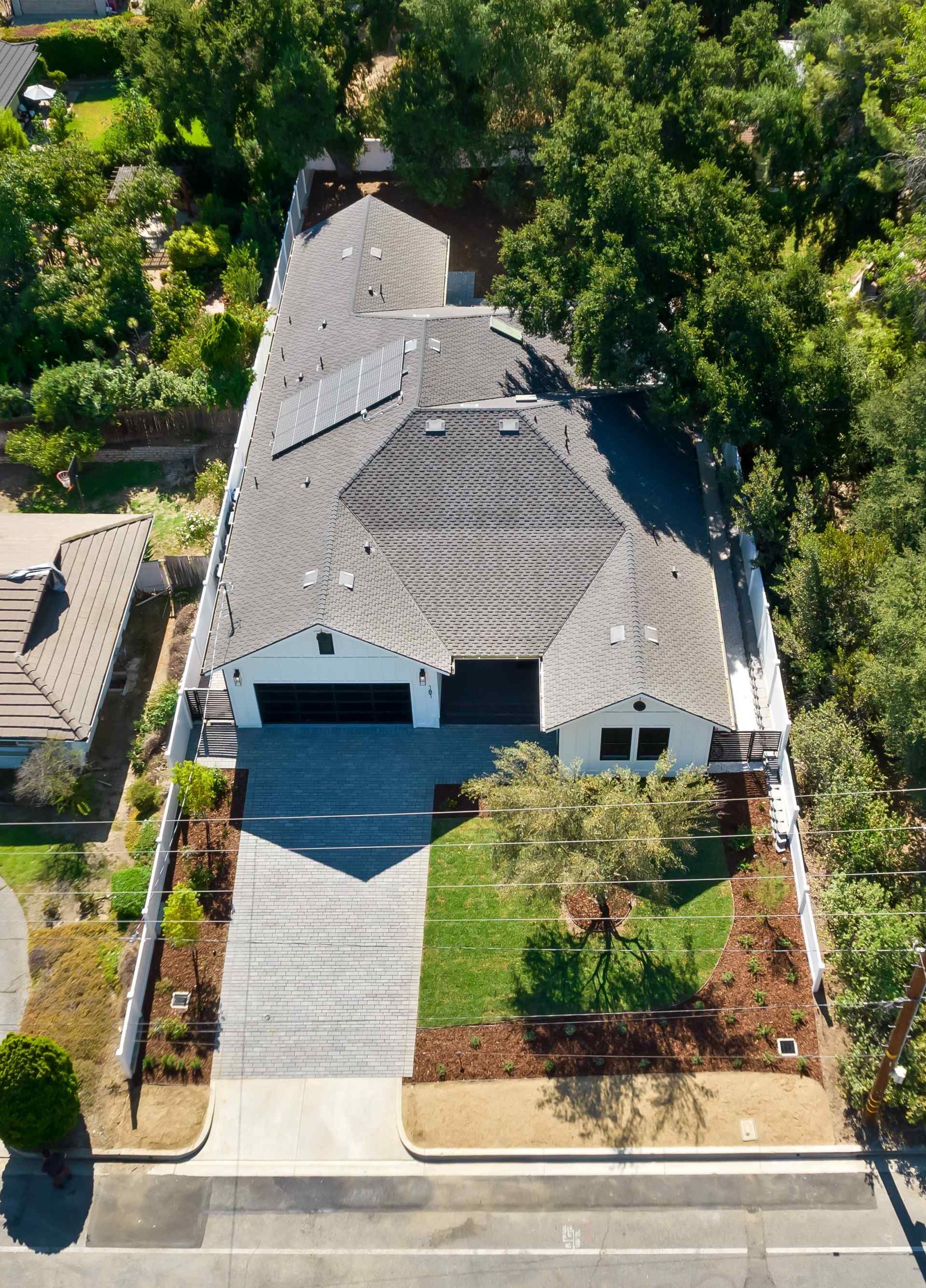 Aerial view of a modern house with a gray tile roof, two-car garage, and a long paved driveway.