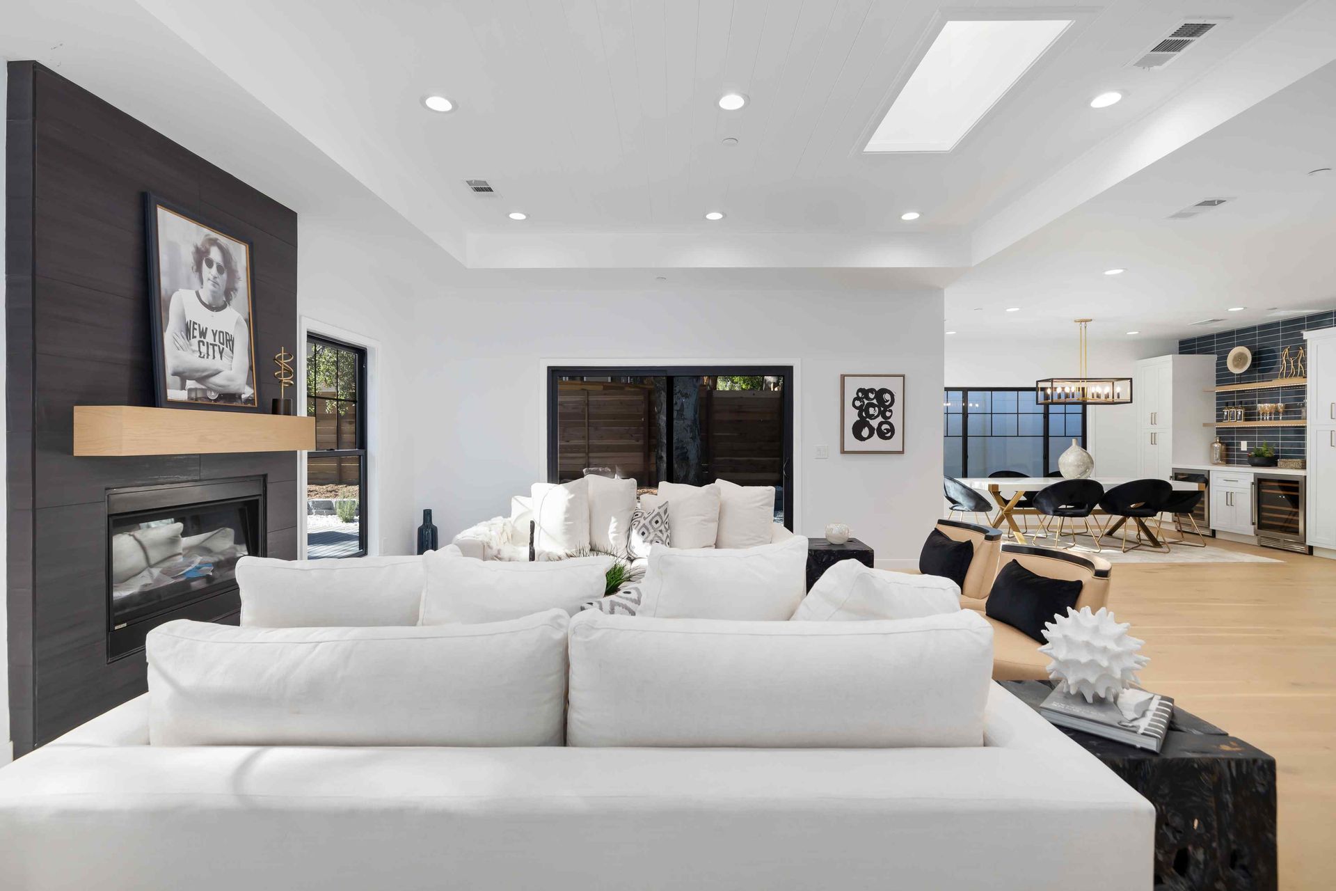 Living room with white sofa, fireplace, and dining area with black accents.