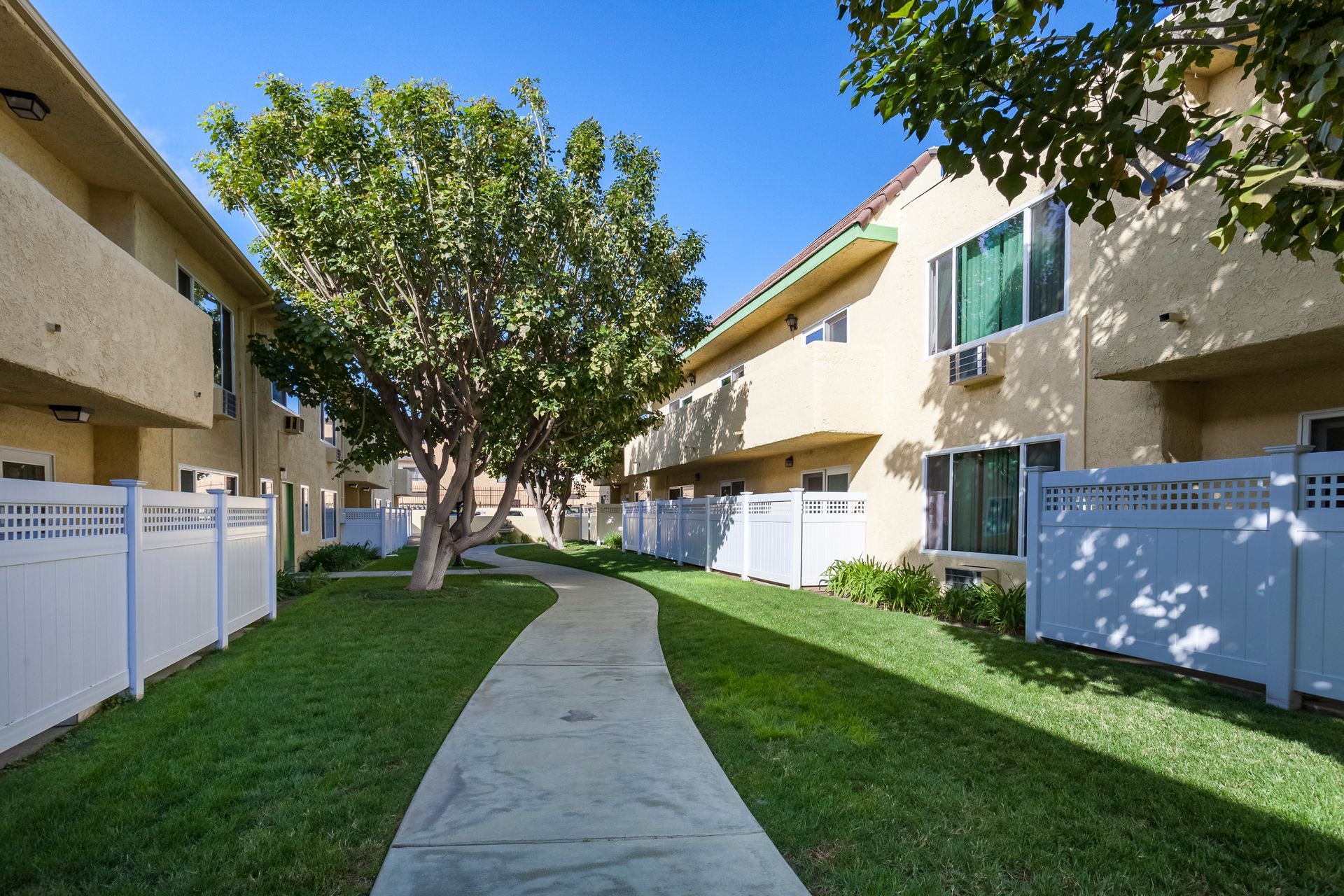 A walkway between two apartment buildings with a white fence