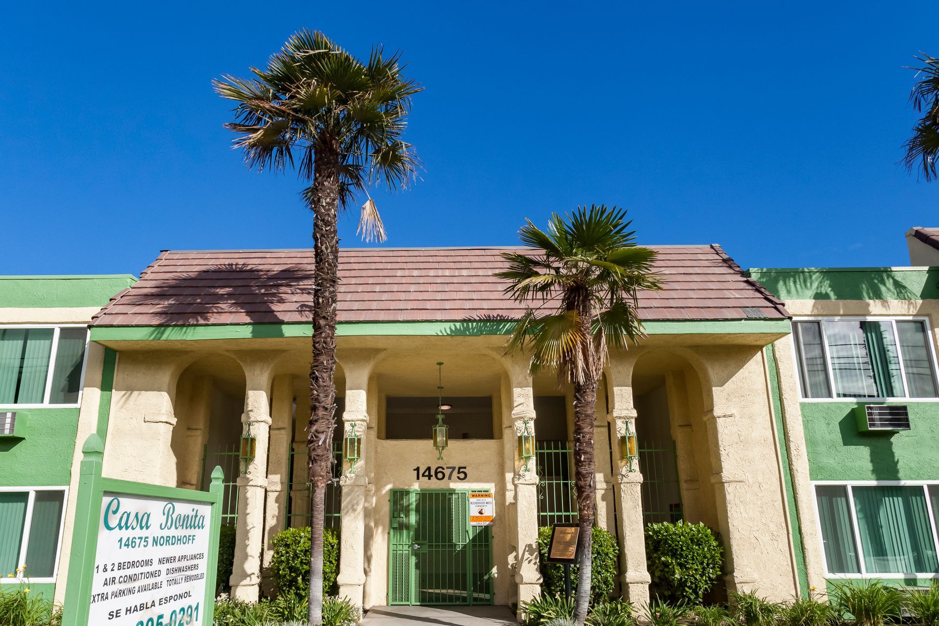 A green building with palm trees in front of it
