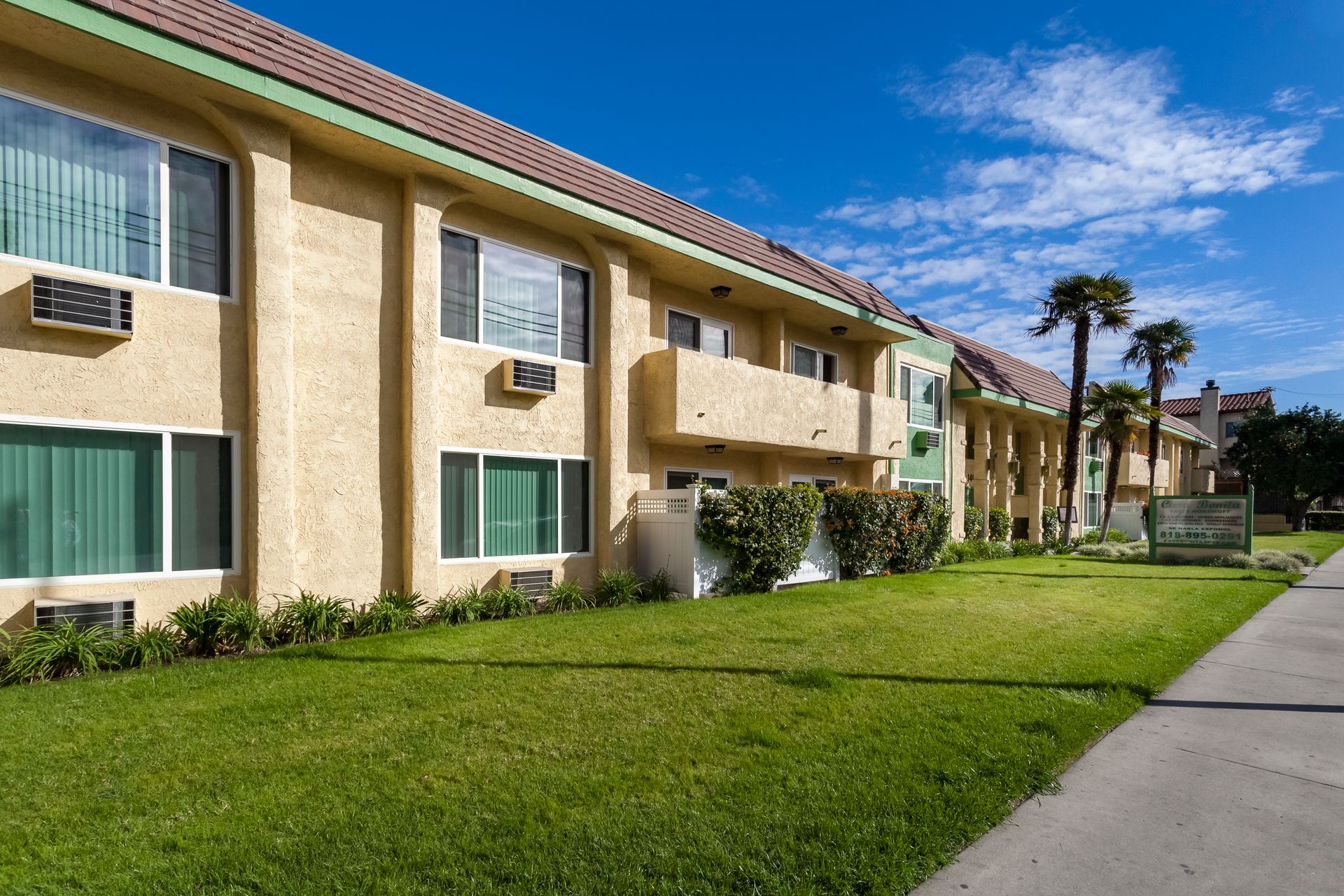A large apartment building with a lush green lawn in front of it