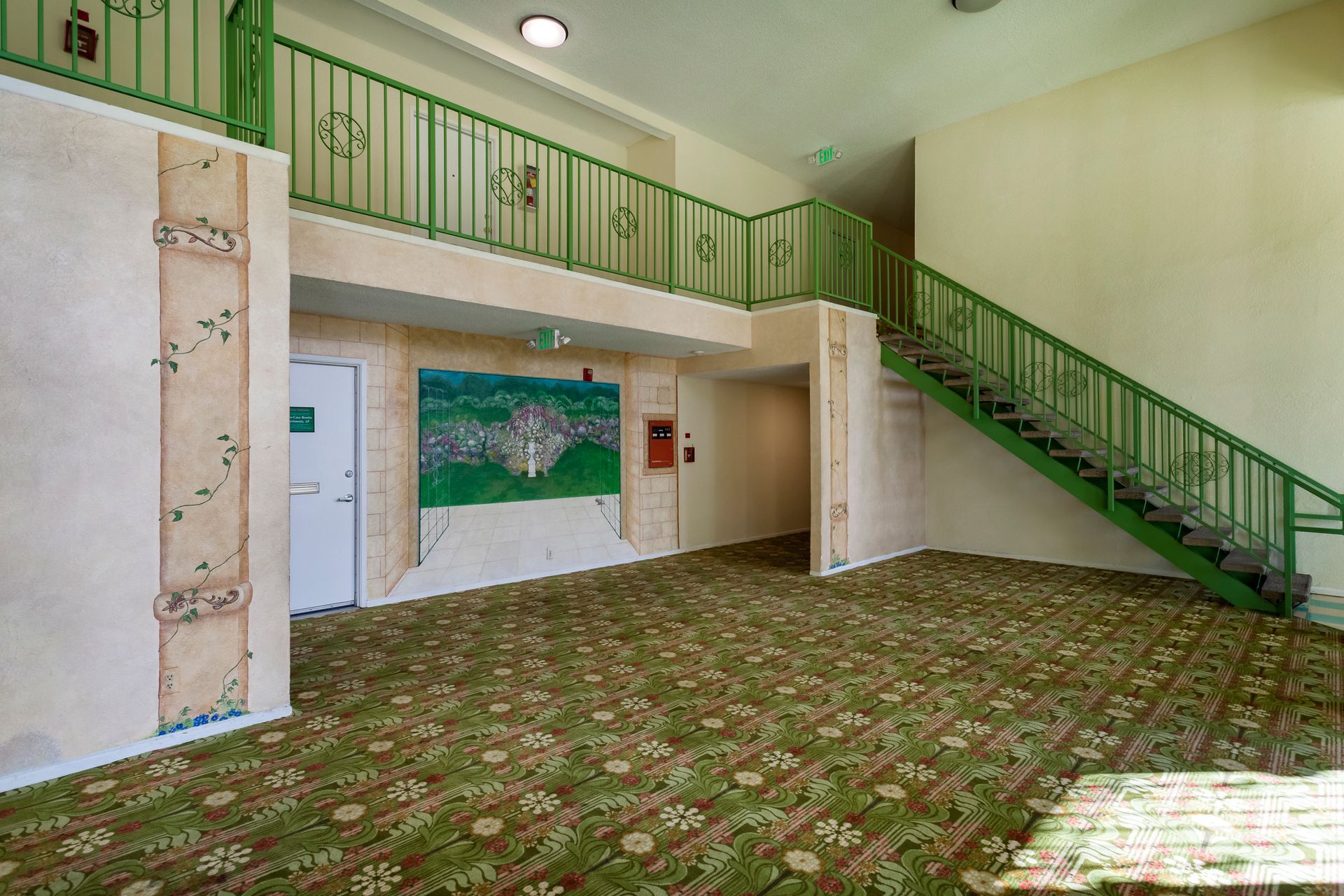 An empty room with a green staircase and a painting on the wall.