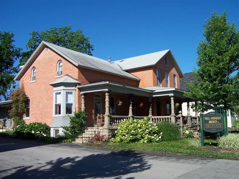 A large brick house with a porch and a sign that says ' funeral home ' on it
