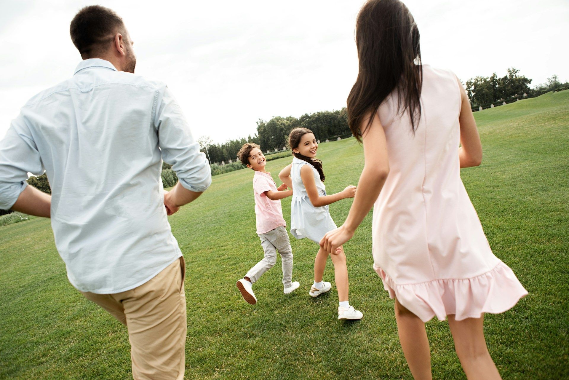 A family is holding hands while walking through a grassy field.