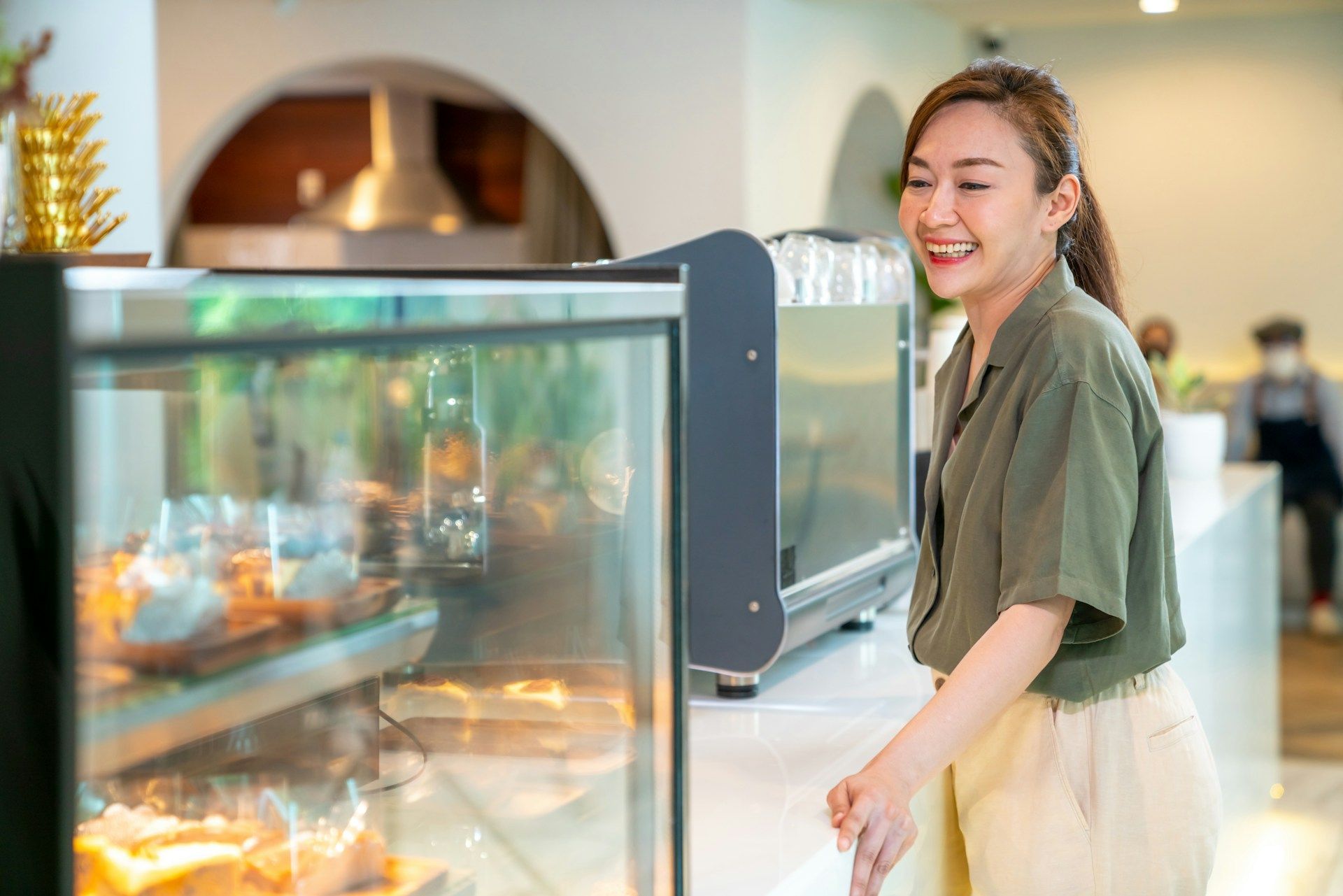 A woman is standing in front of a glass display case in a restaurant.