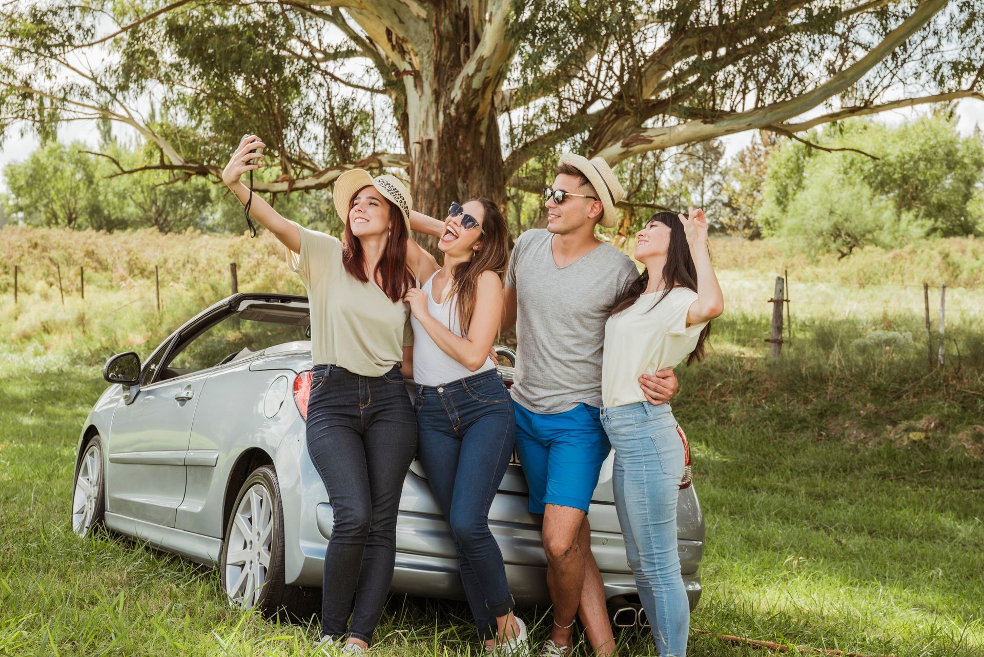 A group of people are taking a selfie in front of a car.