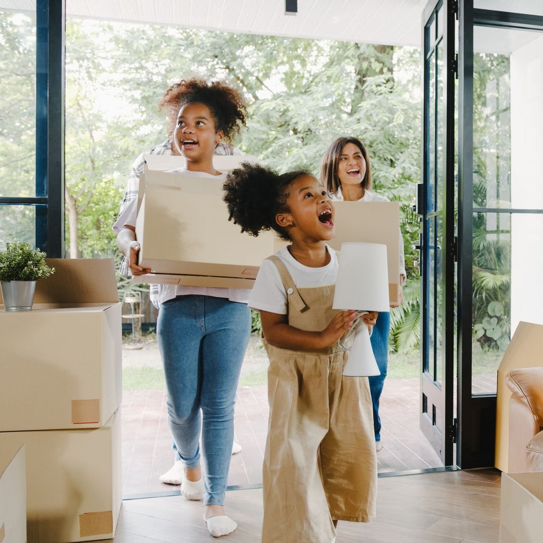 A group of people are carrying boxes into a house.
