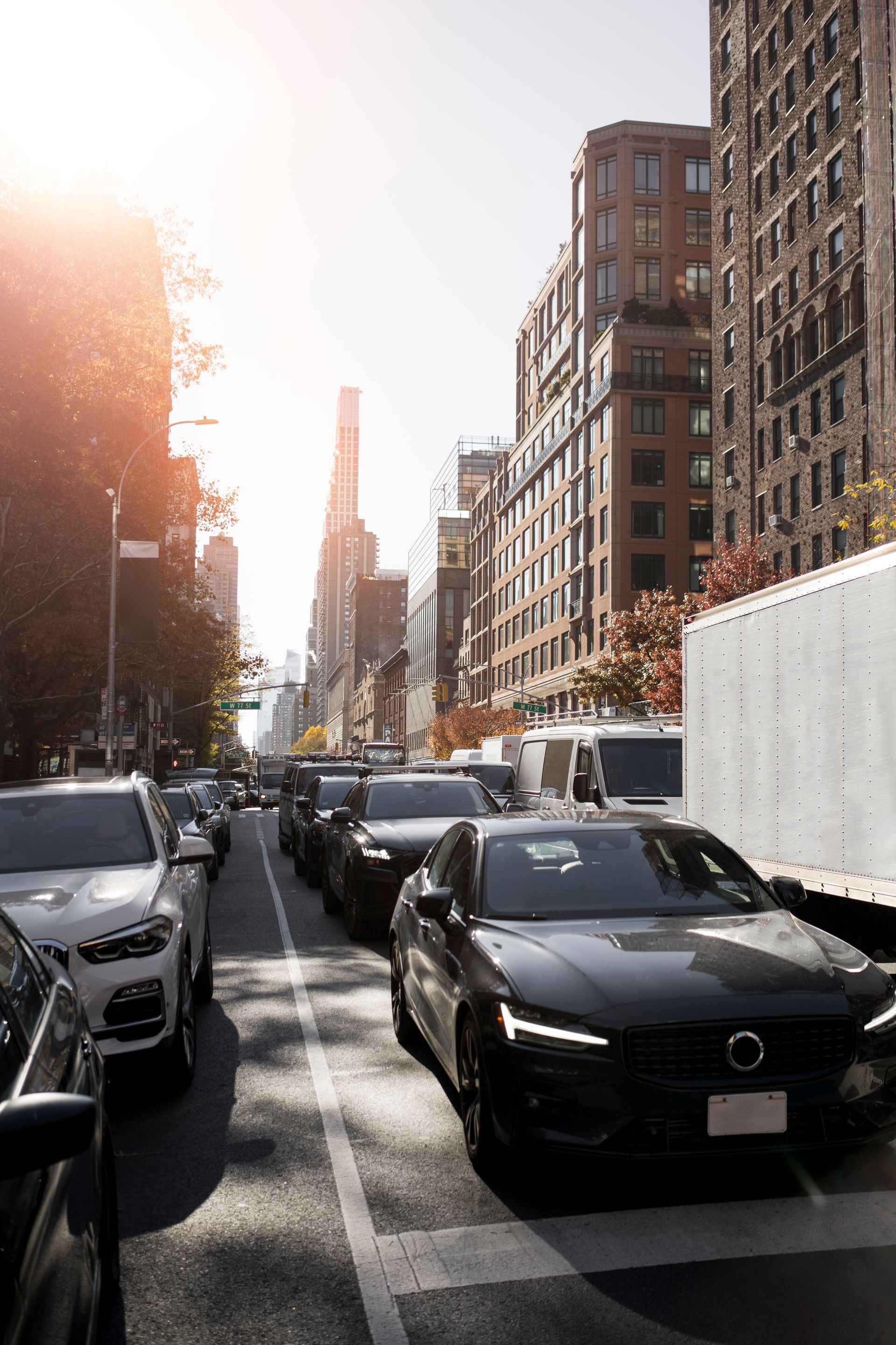 A row of cars are driving down a city street.