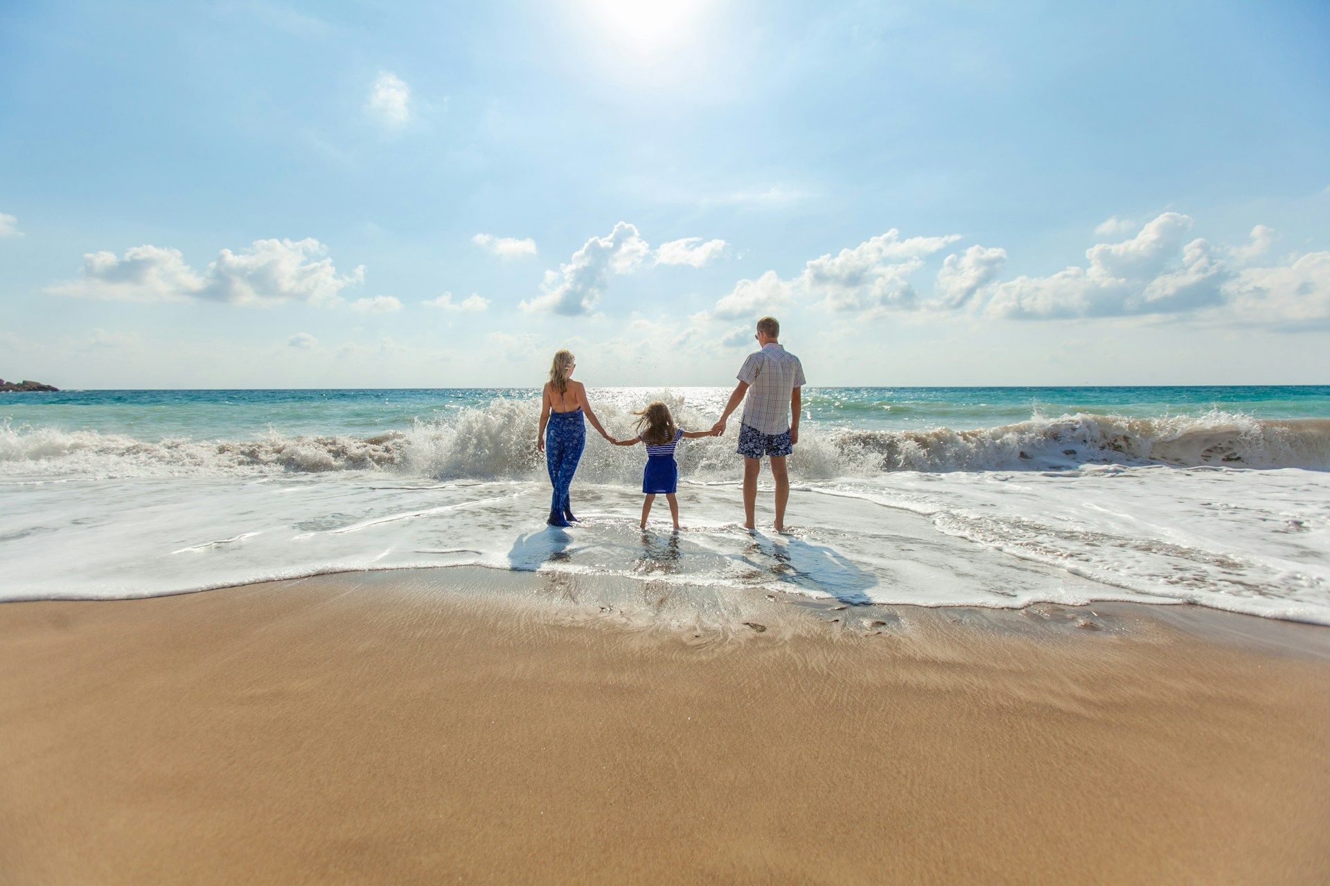 A family is standing on a beach holding hands.