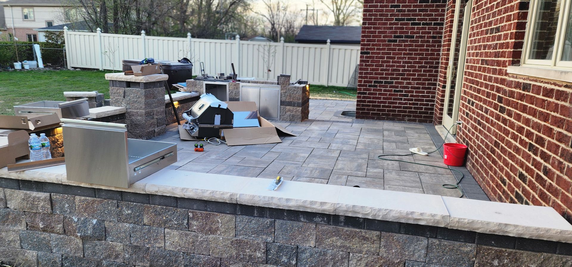Backyard patio with brick wall and outdoor kitchen under construction.