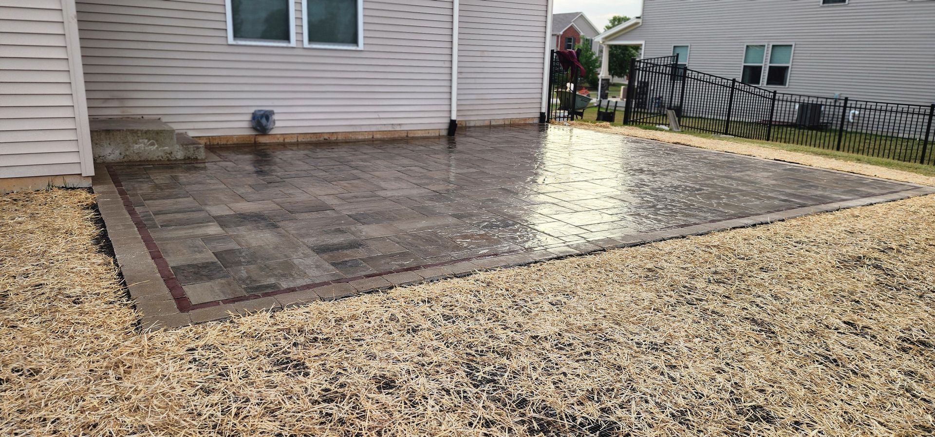 Patio paved with interlocking stones, bordered by gravel, next to a house.