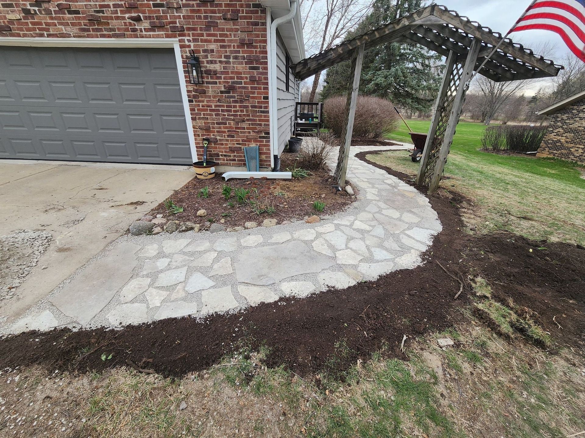 Stone path leads from garage to a shaded area in front yard, lined with fresh mulch.