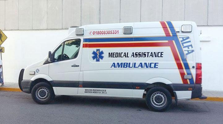 Ambulancia blanca con franjas rojas y azules, logo “ALFA” y texto “AMBULANCIA DE ASISTENCIA MÉDICA” en el lateral.