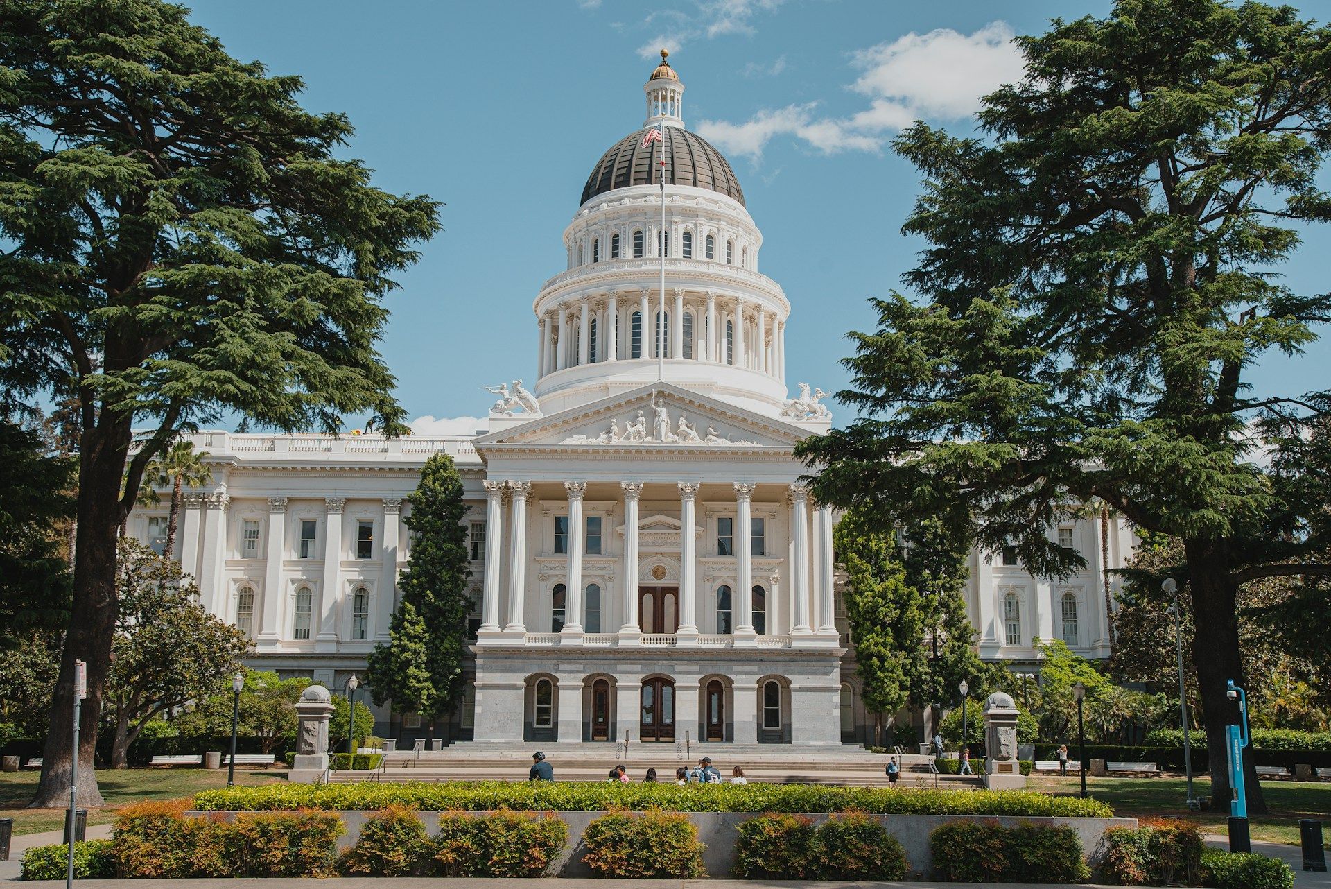 The capitol building in california is surrounded by trees and bushes.