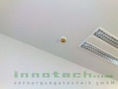 Ein Rauchmelder wird an der Decke eines Raumes montiert.
