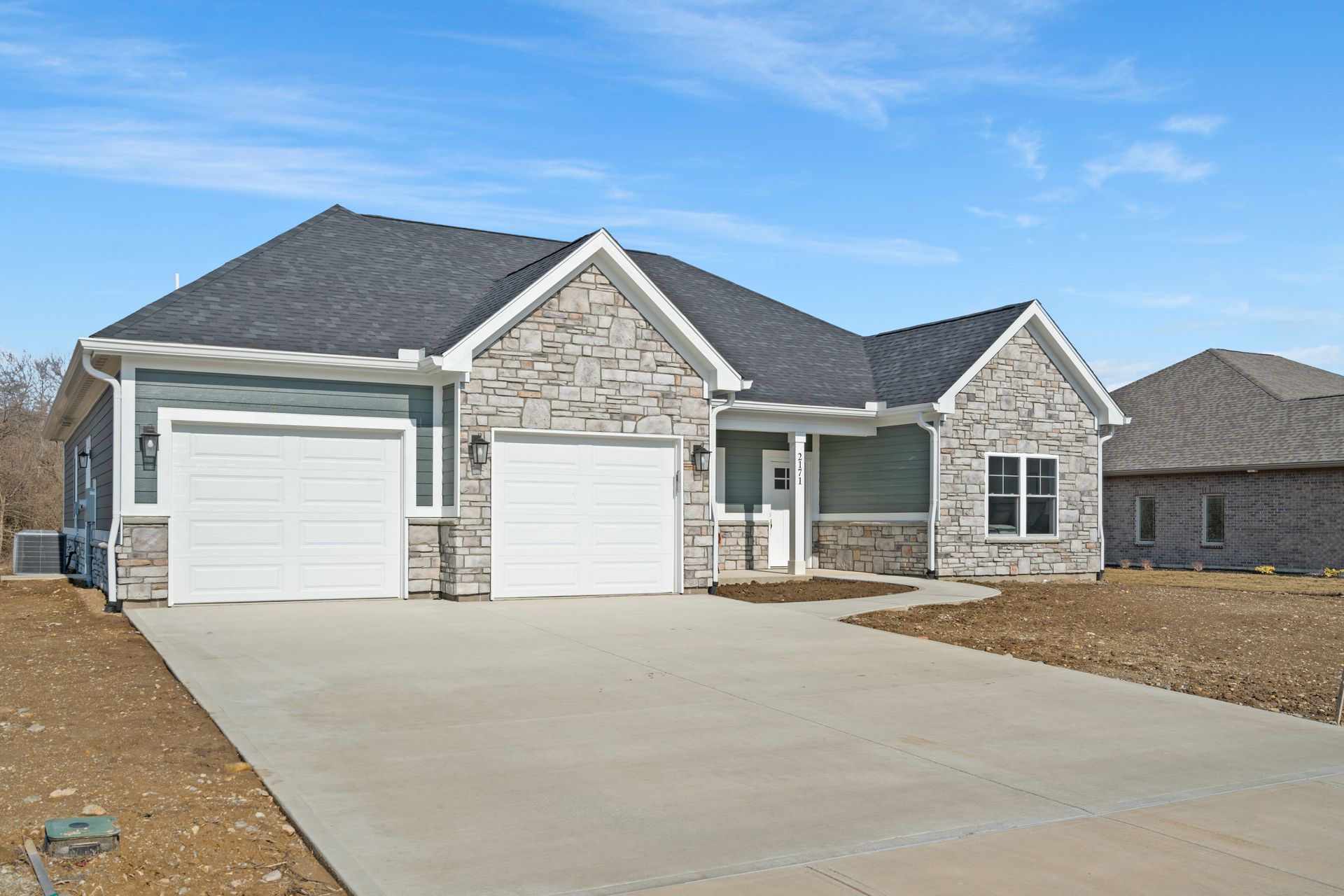 A house with two garage doors and a concrete driveway in front of it.