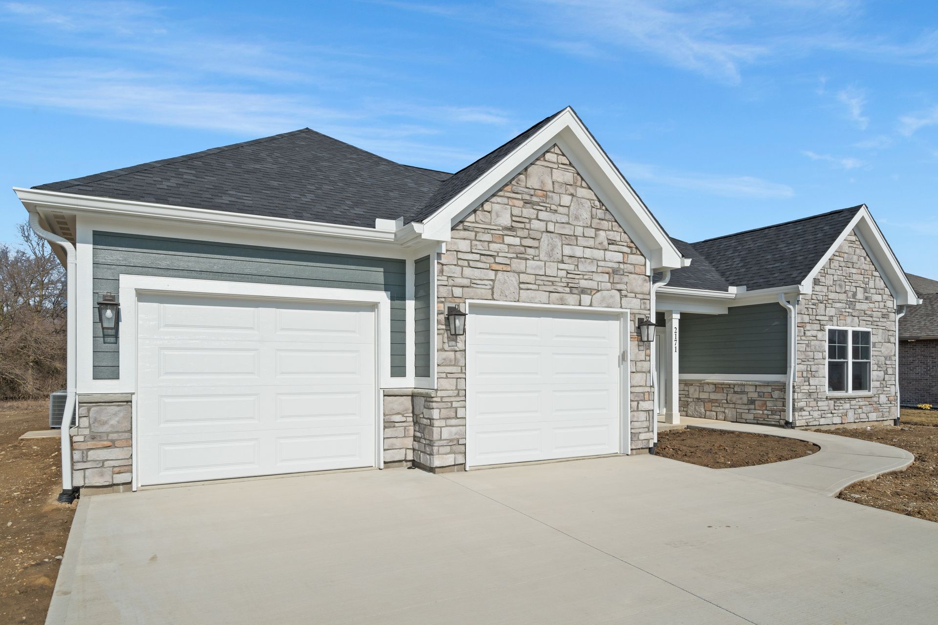 A house with two garage doors and a stone facade.