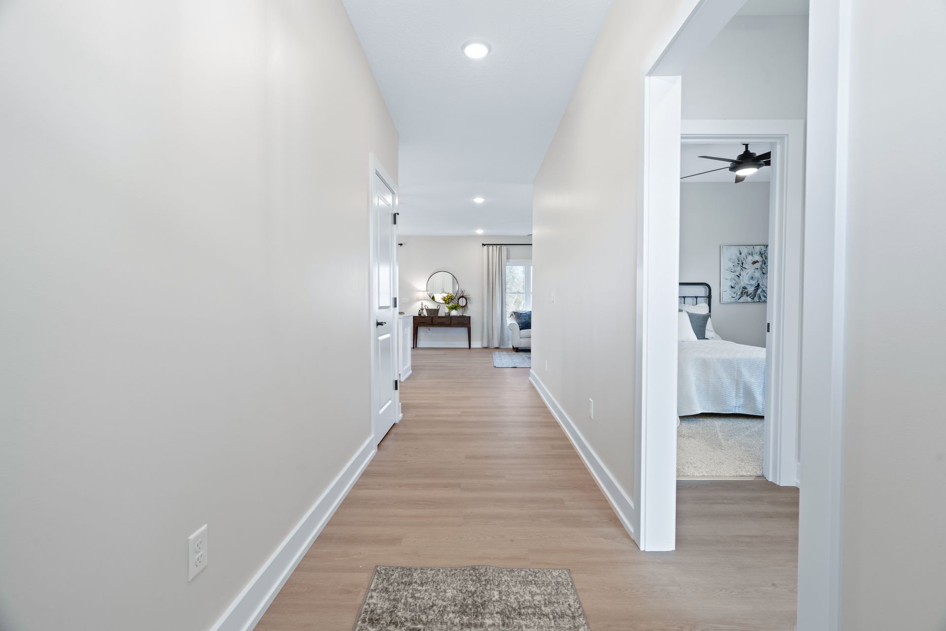 A long hallway leading to a bedroom and a living room in a house.
