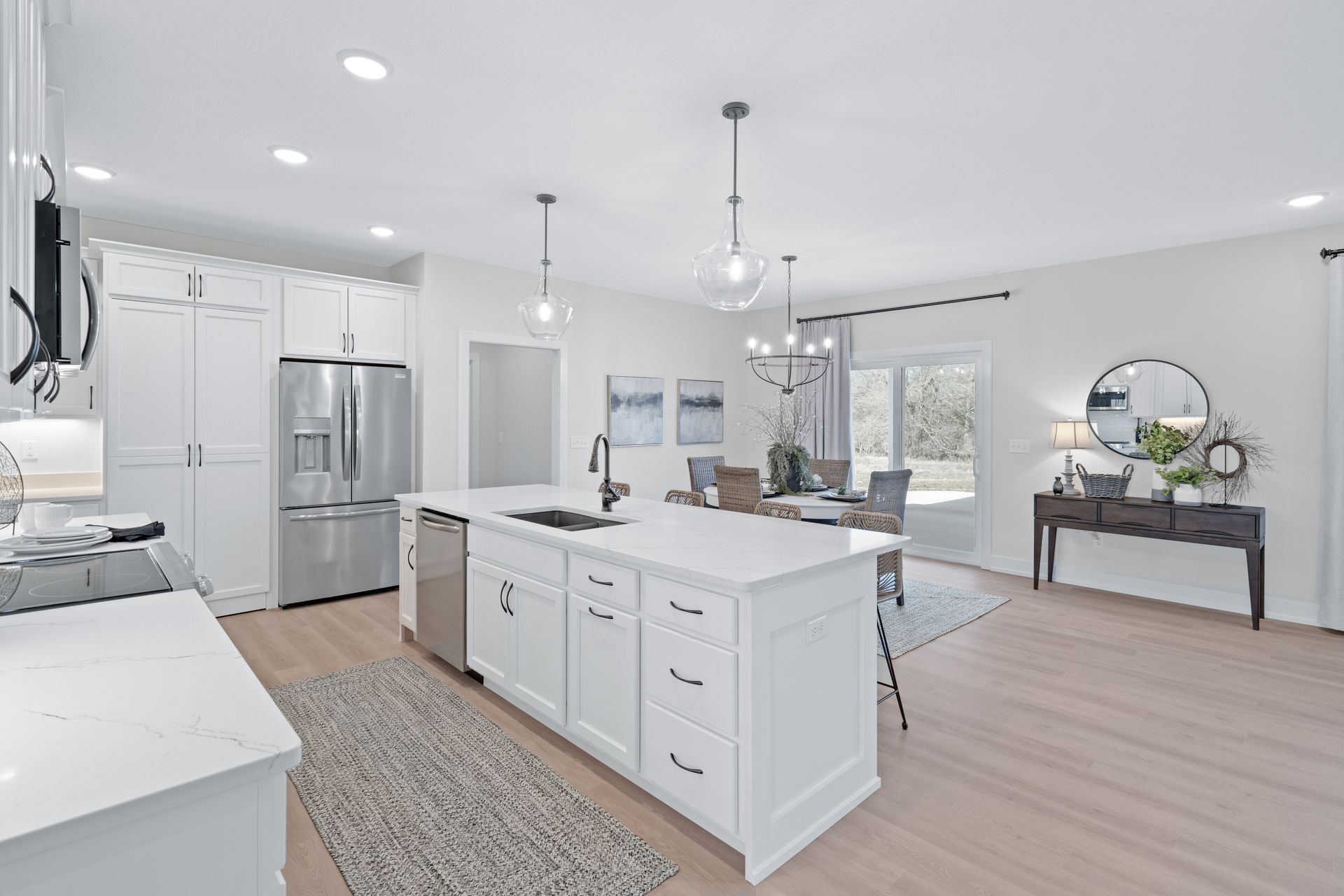 A kitchen with white cabinets and stainless steel appliances and a large island in the middle.