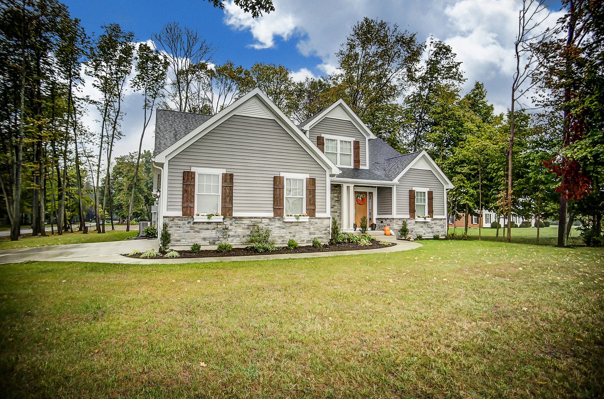 A large white house with a blue roof is surrounded by trees and grass.