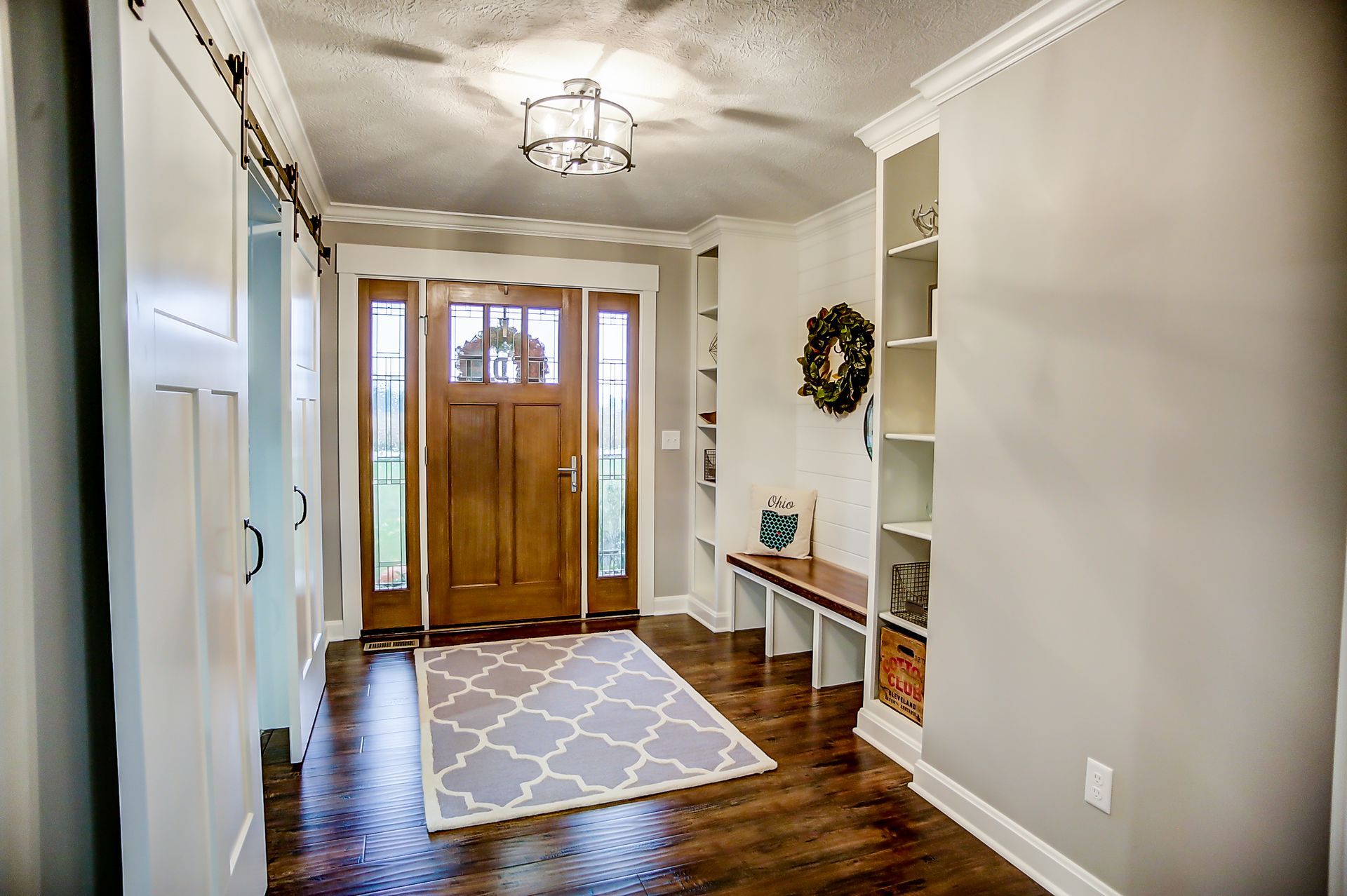 A hallway in a house with a wooden door and a rug.