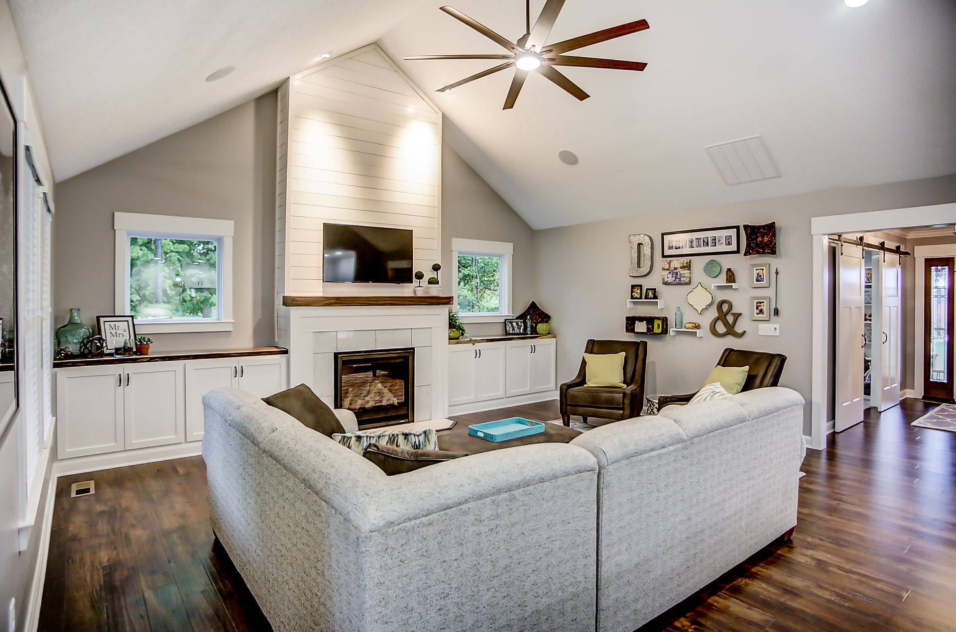 A living room with a couch , fireplace , television and ceiling fan.