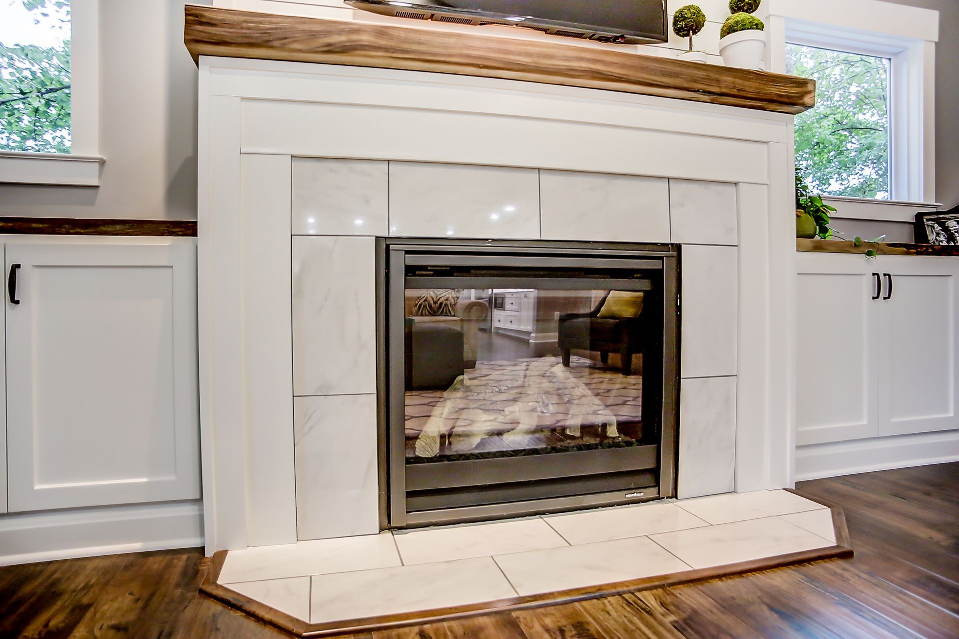 A fireplace with a glass door and a wooden mantle in a living room.
