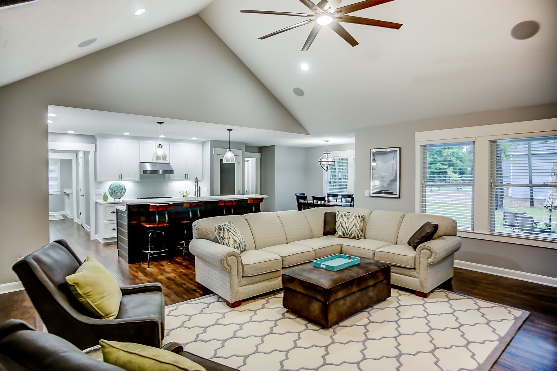 A living room with a sectional couch and a ceiling fan