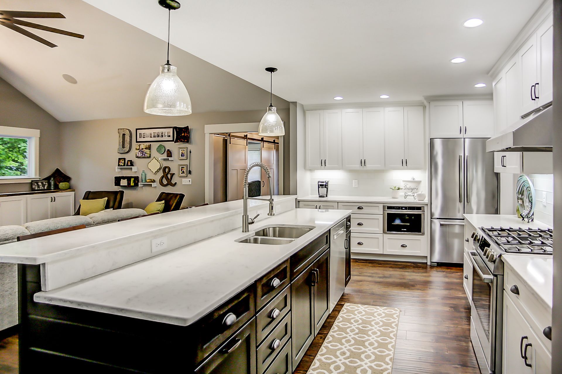 A kitchen with white cabinets and stainless steel appliances and a large island in the middle.