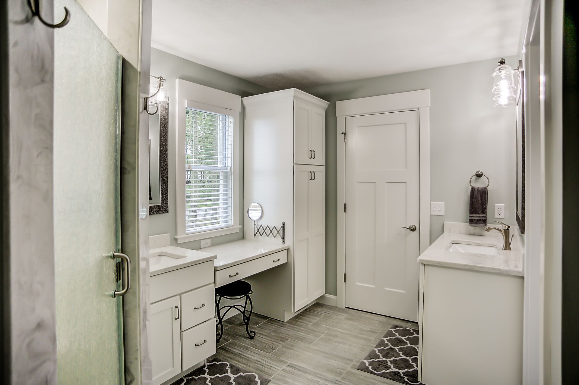 A bathroom with a vanity , sink , mirror and walk in shower.
