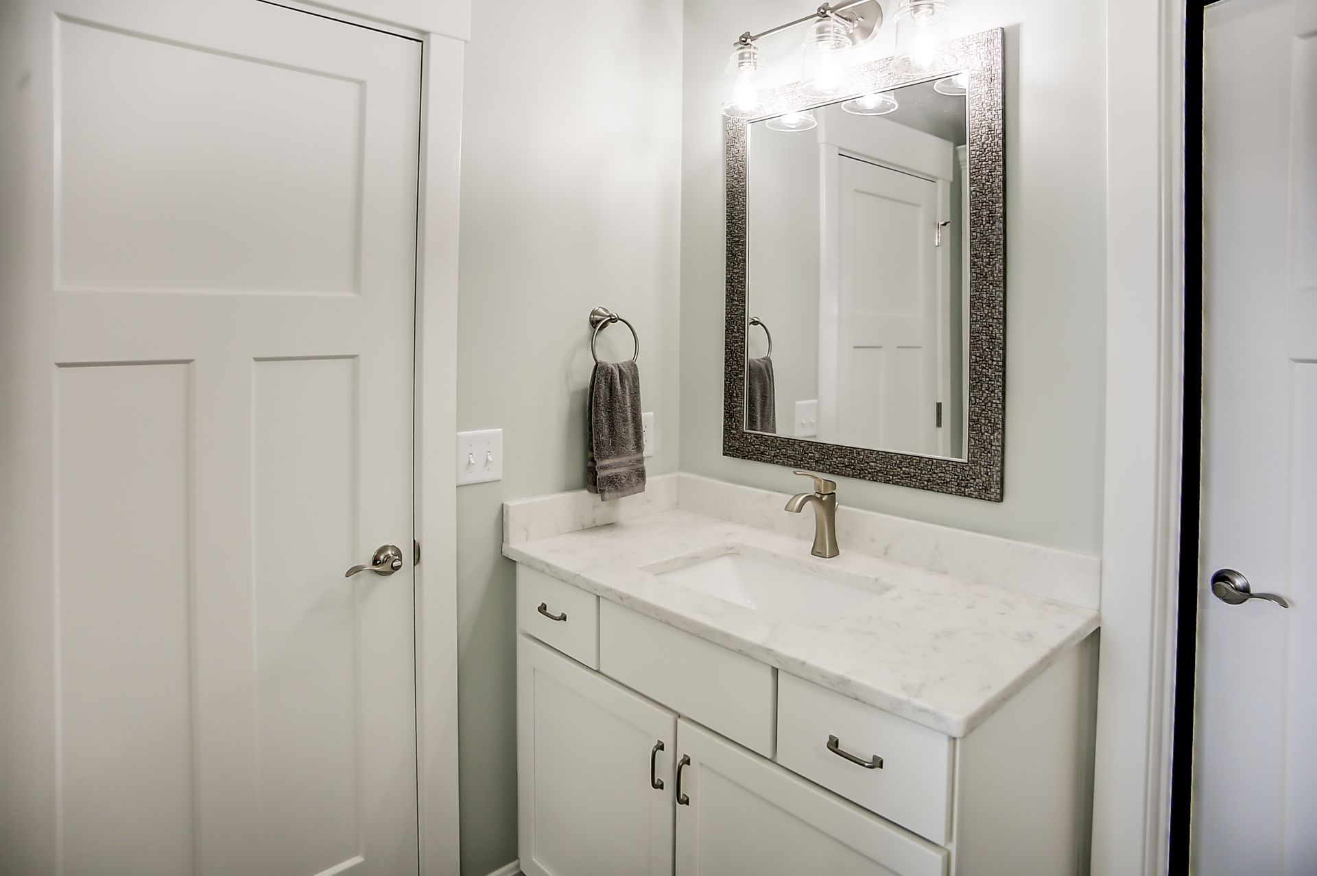 A bathroom with a sink , mirror and towel rack.