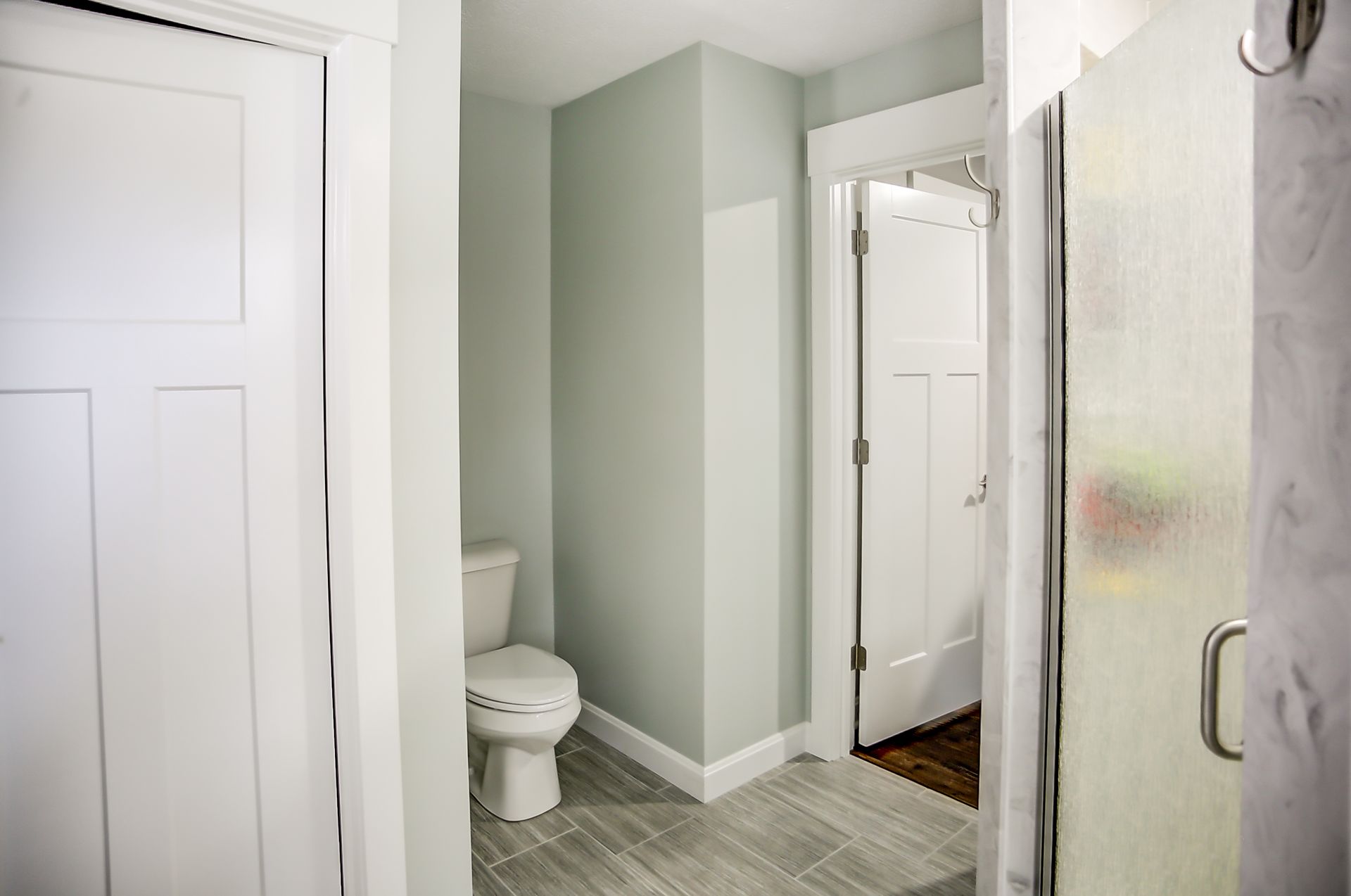 A bathroom with a toilet , shower and closet.