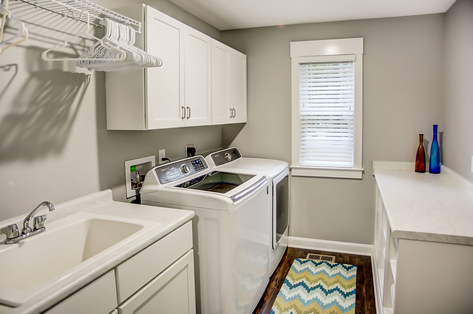A laundry room with a washer and dryer , sink , and window.