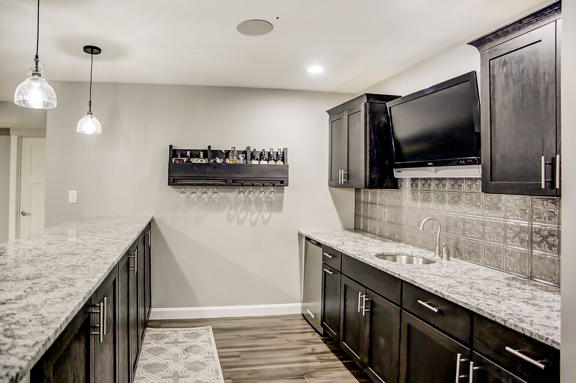A kitchen with granite counter tops and black cabinets.