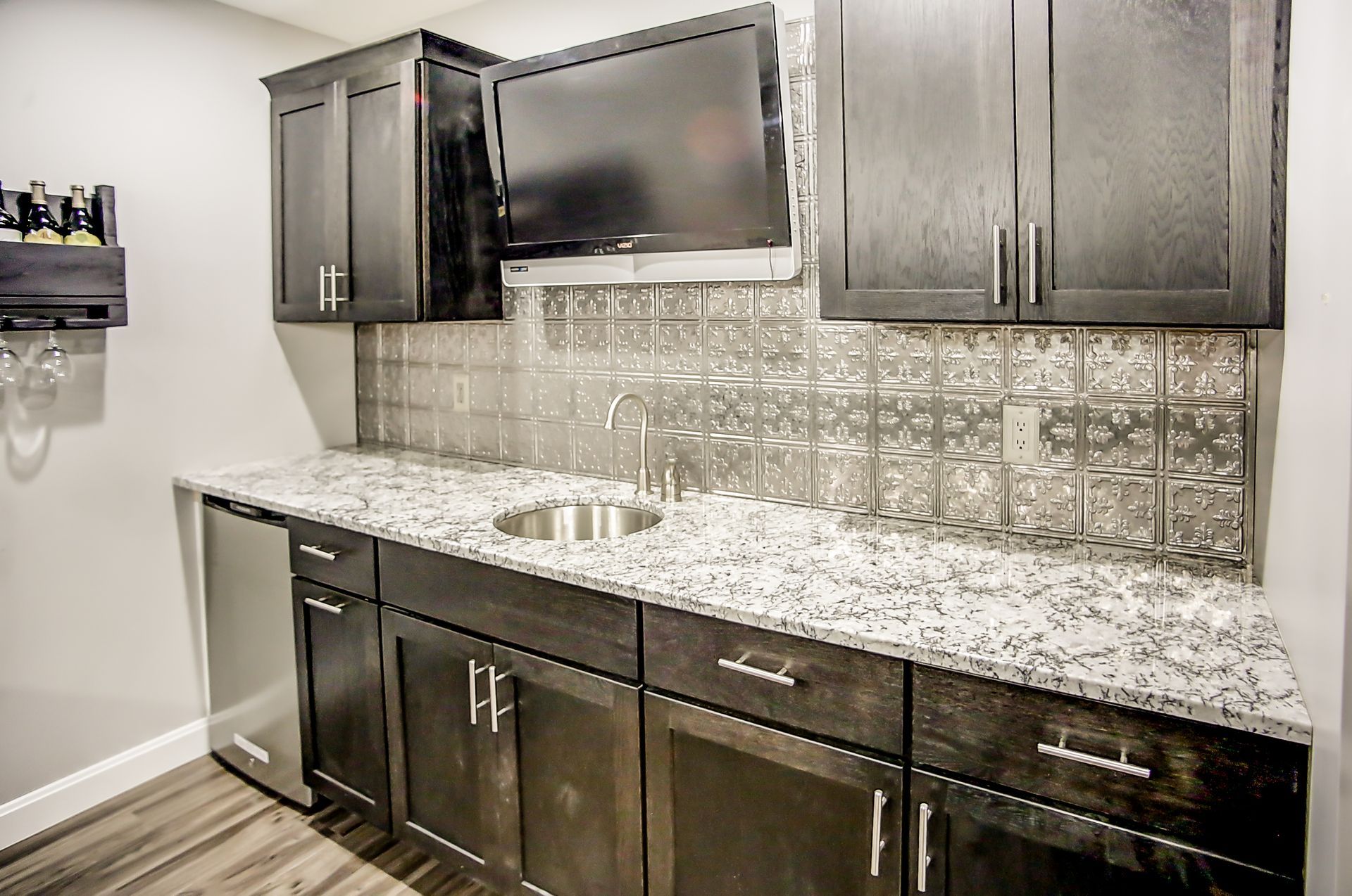 A kitchen with granite counter tops , stainless steel appliances , and black cabinets.