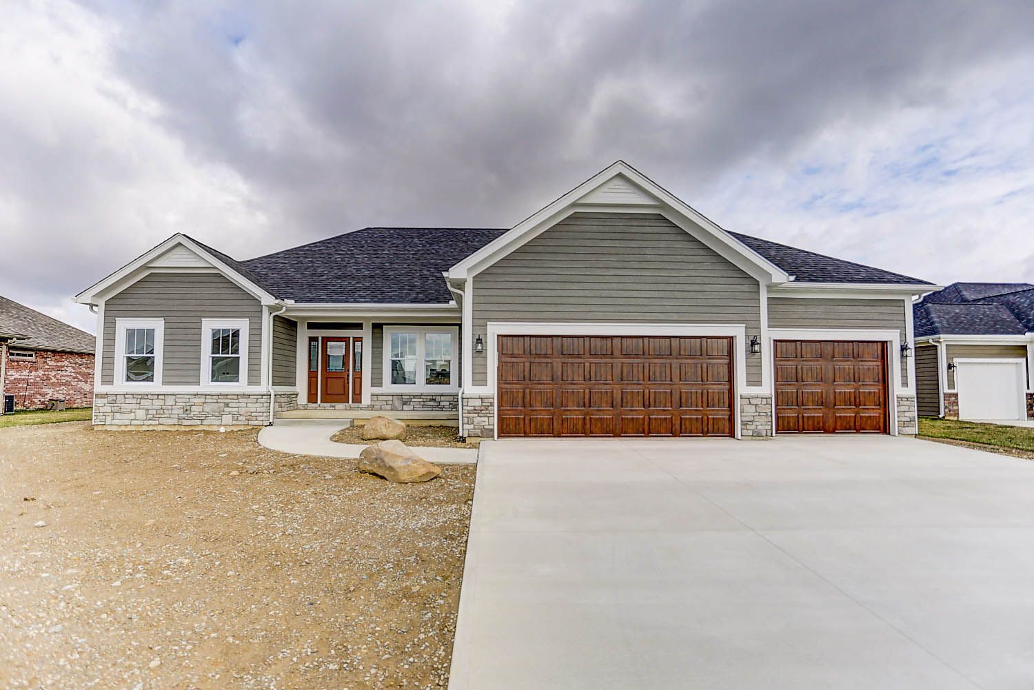 A large gray house with two garage doors and a concrete driveway.