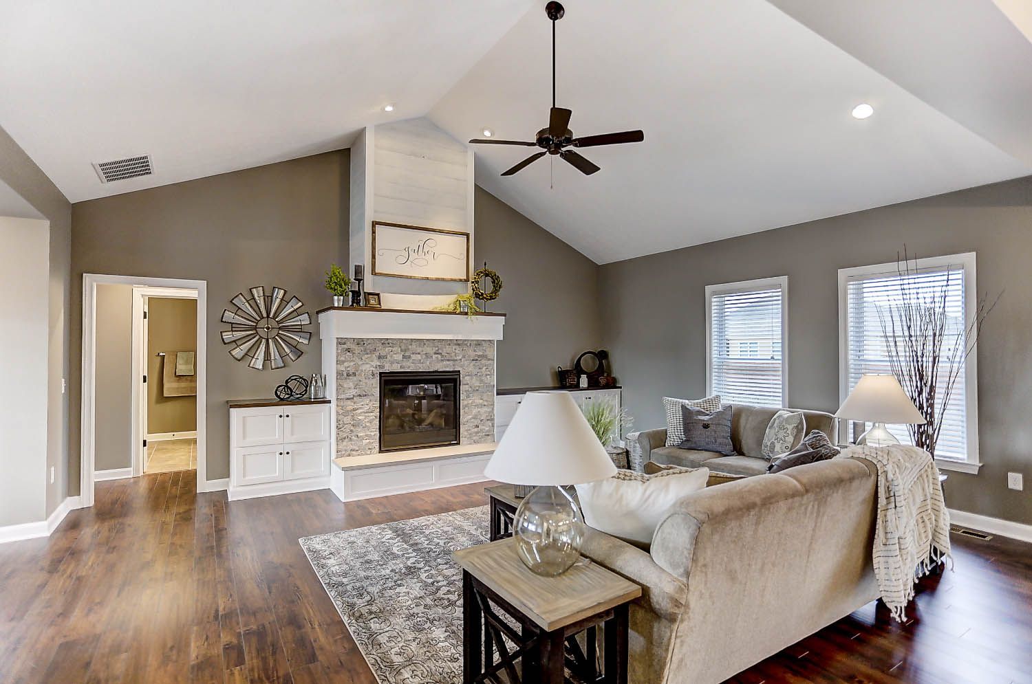 A living room with a couch , fireplace and ceiling fan.
