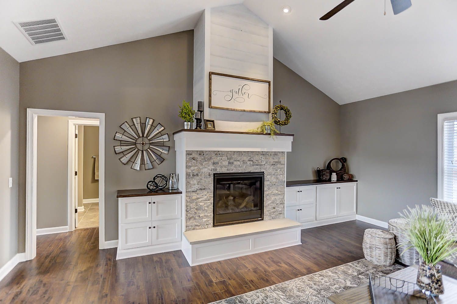 A living room with a fireplace and a ceiling fan.