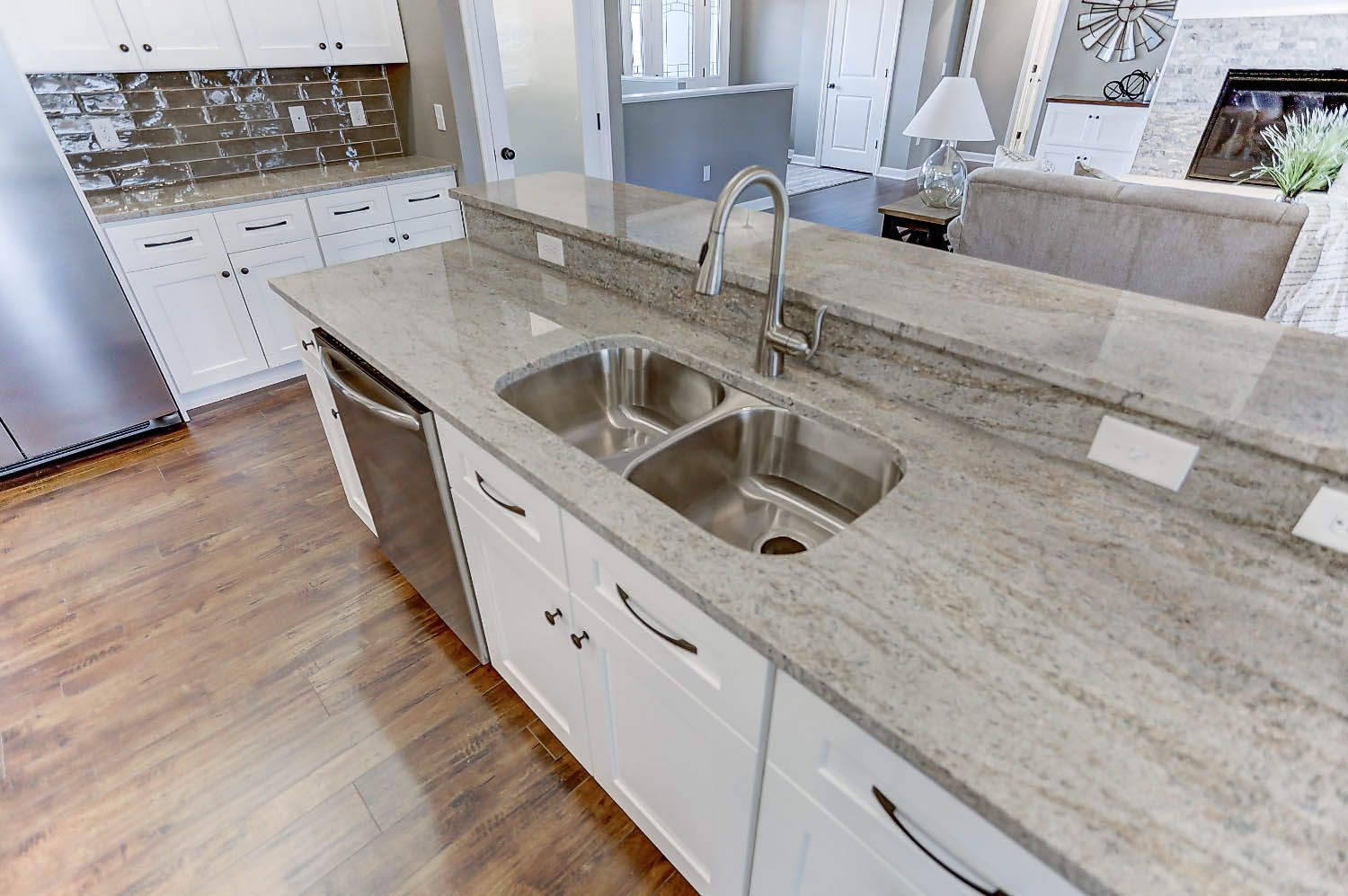 A kitchen with a stainless steel sink and granite counter tops.