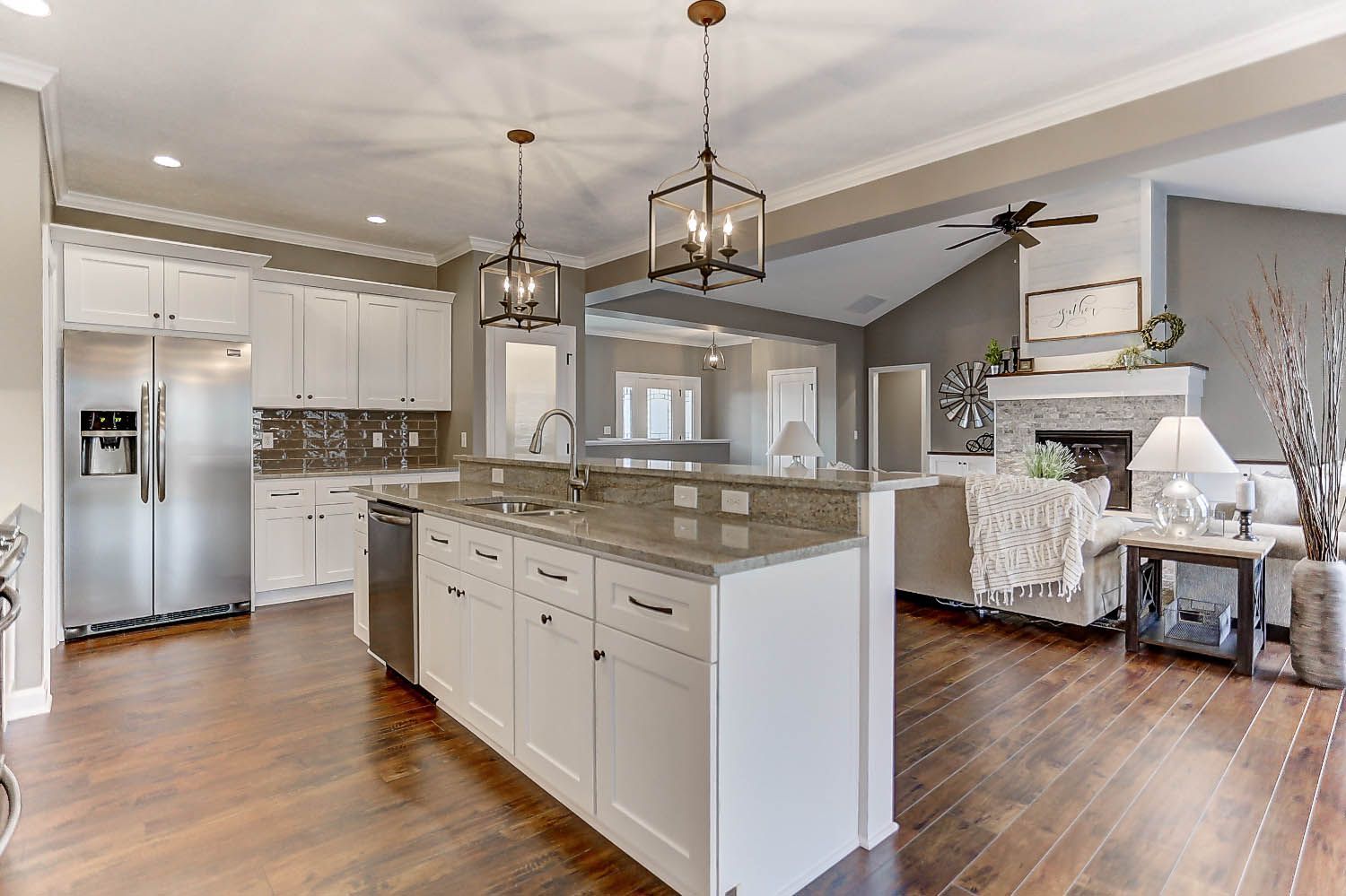 A kitchen with white cabinets , granite counter tops , stainless steel appliances and hardwood floors.