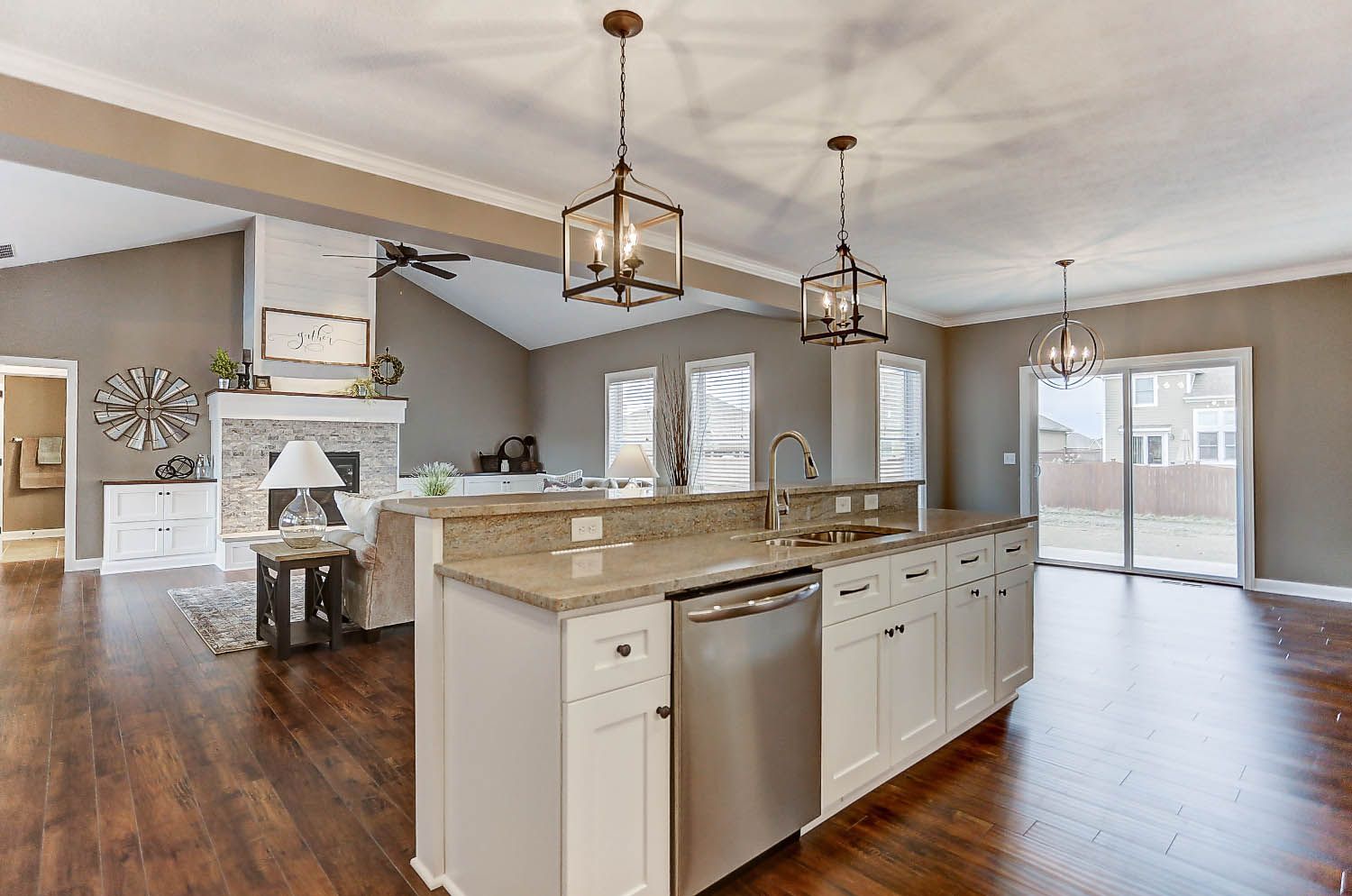 A kitchen with white cabinets , granite counter tops , stainless steel appliances and hardwood floors.