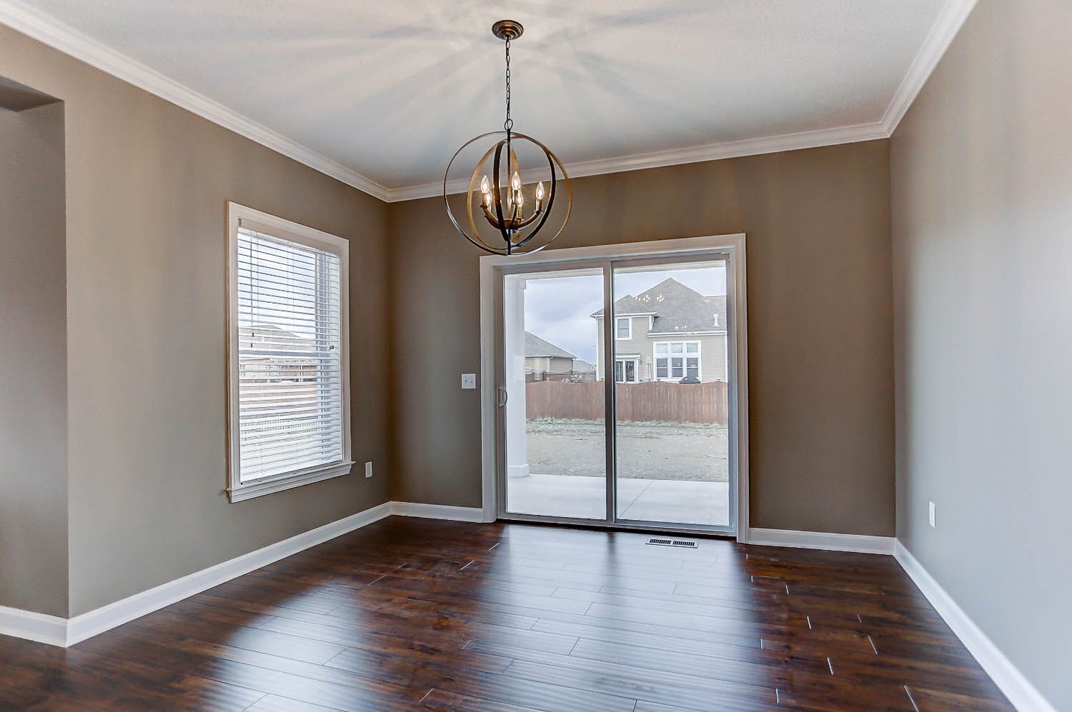 An empty room with a sliding glass door and a chandelier hanging from the ceiling.