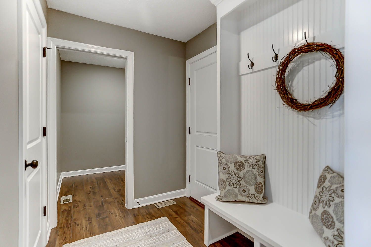 A hallway with a bench and a mirror on the wall.