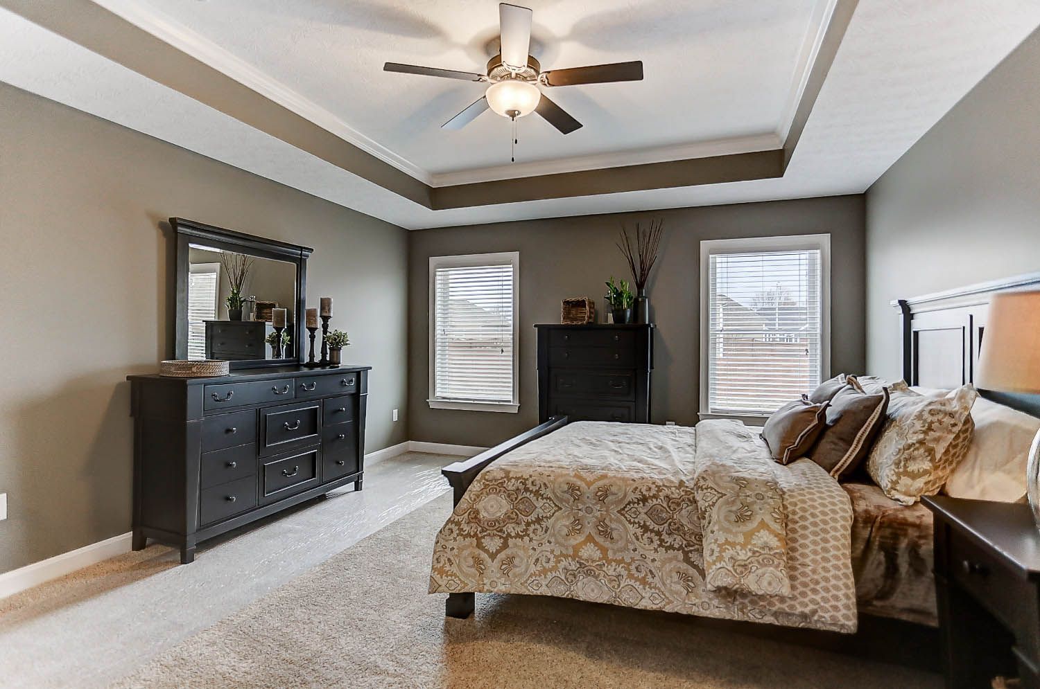 A bedroom with a bed , dresser , mirror and ceiling fan.