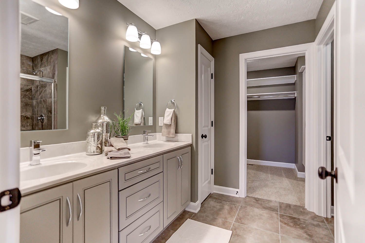 A bathroom with two sinks , a mirror and a walk in closet.